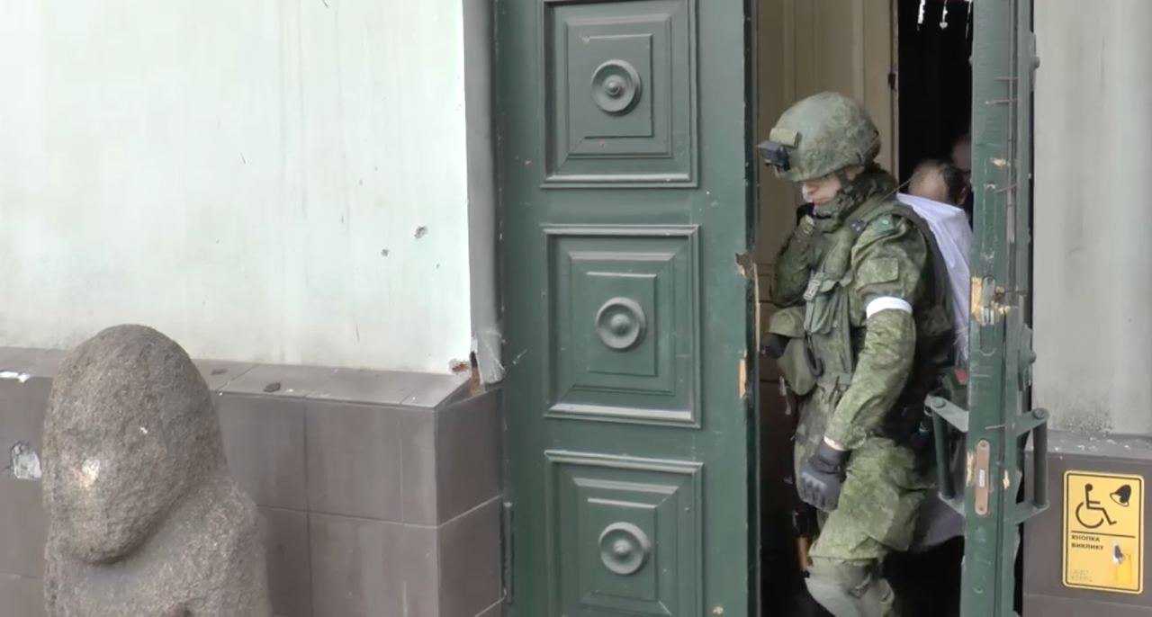 Російський окупант виходить з дверей музею в Маріуполі. 